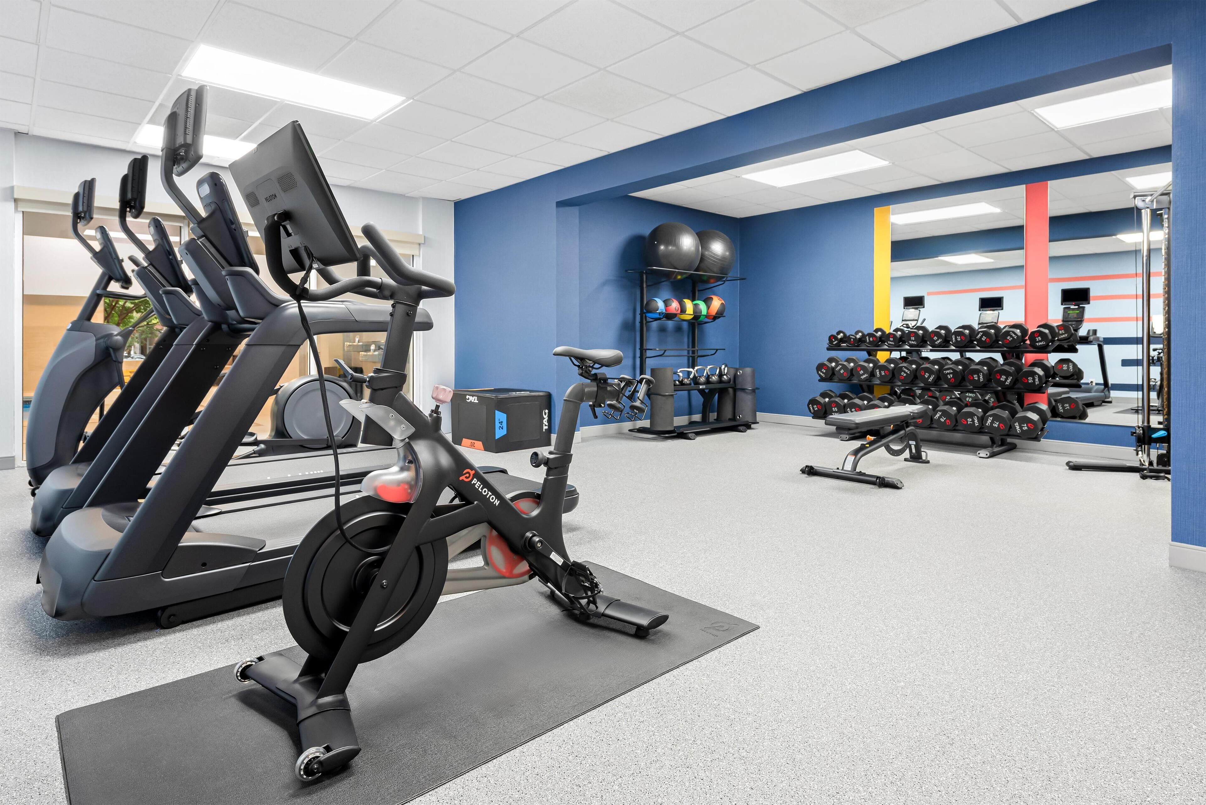 A gym with treadmills, an elliptical, and a rack of dumbbells.