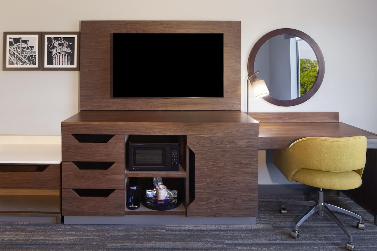 A modern room with a built-in TV, a microwave, and a yellow chair.