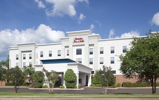 A white building with a sign reading 'Hampton Inn & Suites.'