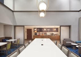 A conference room with a long table, chairs, a kitchenette, and a bar area.