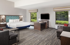 A hotel room with a bed, desk, TV, and seating area. - Hampton Inn & Suites Natchez (Natchez)