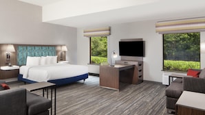 A hotel room with a bed, desk, TV, and seating area. - Hampton Inn & Suites Natchez (Natchez)