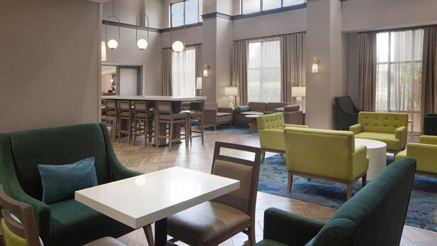 A hotel lobby with a dining area, seating arrangements, and large windows. - Hampton Inn & Suites Natchez (Natchez)