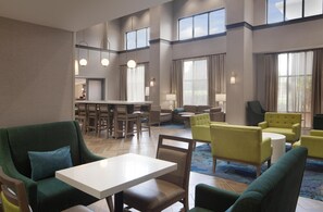 A hotel lobby with a dining area, seating arrangements, and large windows. - Hampton Inn & Suites Natchez (Natchez)