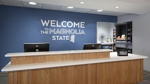 A reception desk with a blue wall and a sign that reads 'WELCOME TO THE MAGNOLIA STATE'. - Hampton Inn & Suites Natchez (Natchez)