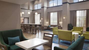 A hotel lobby with a dining area, seating arrangements, and large windows.