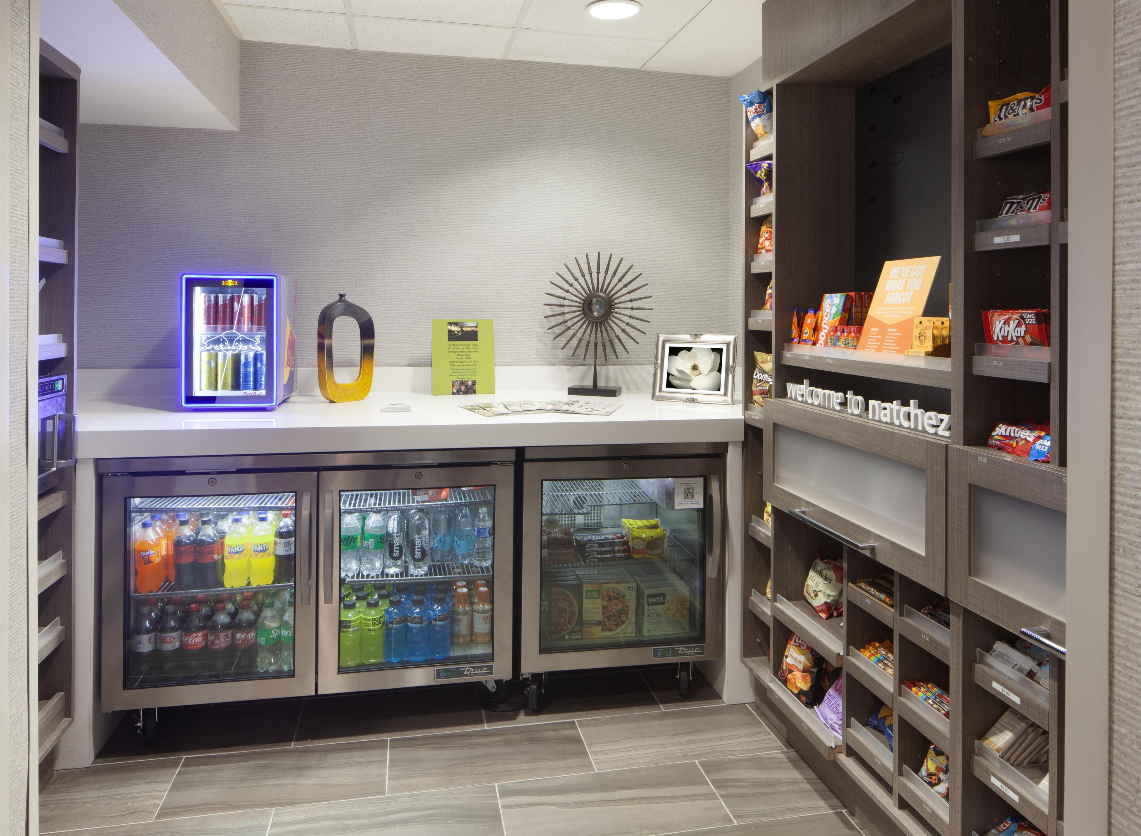 A self-service beverage station with refrigerated drink dispensers, a neon sign, and a snack shelf.