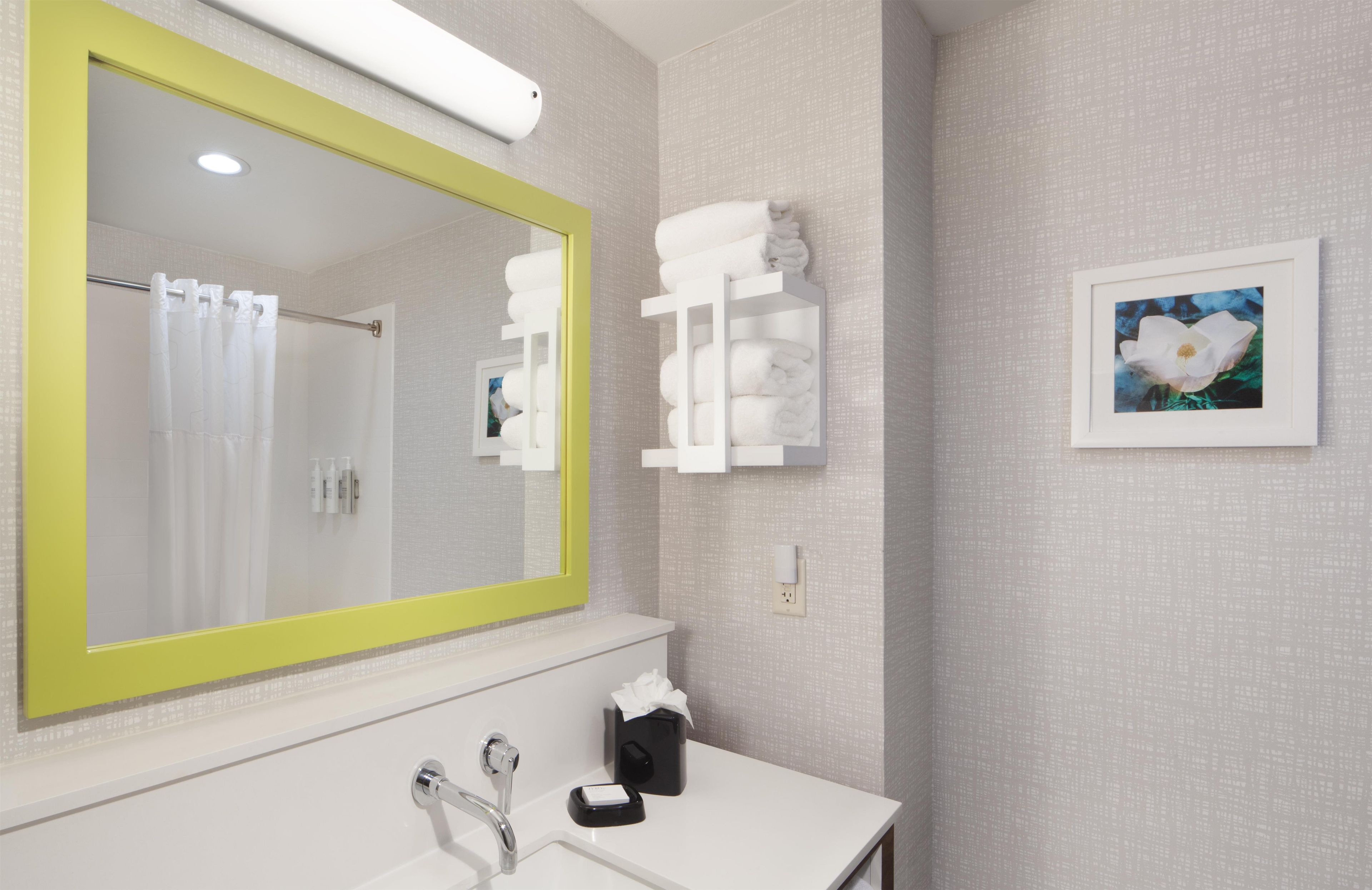 A bathroom with a large mirror, a sink, a towel rack, and a framed picture on the wall.