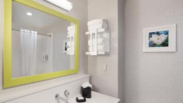 A bathroom with a large mirror, a sink, a towel rack, and a framed picture on the wall.