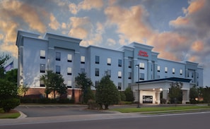 A modern hotel with a flat roof, multiple windows, and a prominent sign.