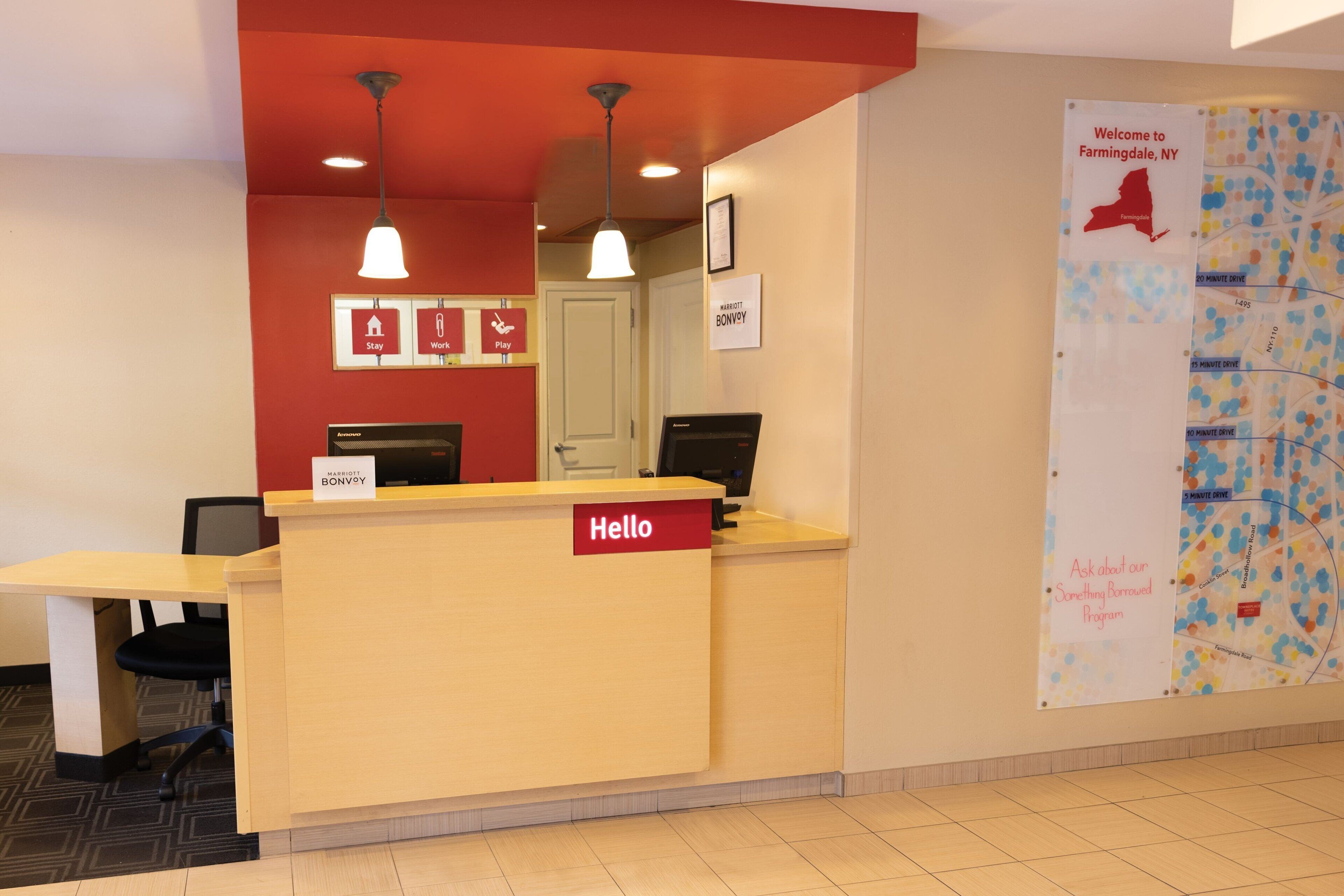 A reception desk with a 'Hello' sign, a map of Farmingdale, NY, and a 'Welcome to Farmingdale, NY' sign.