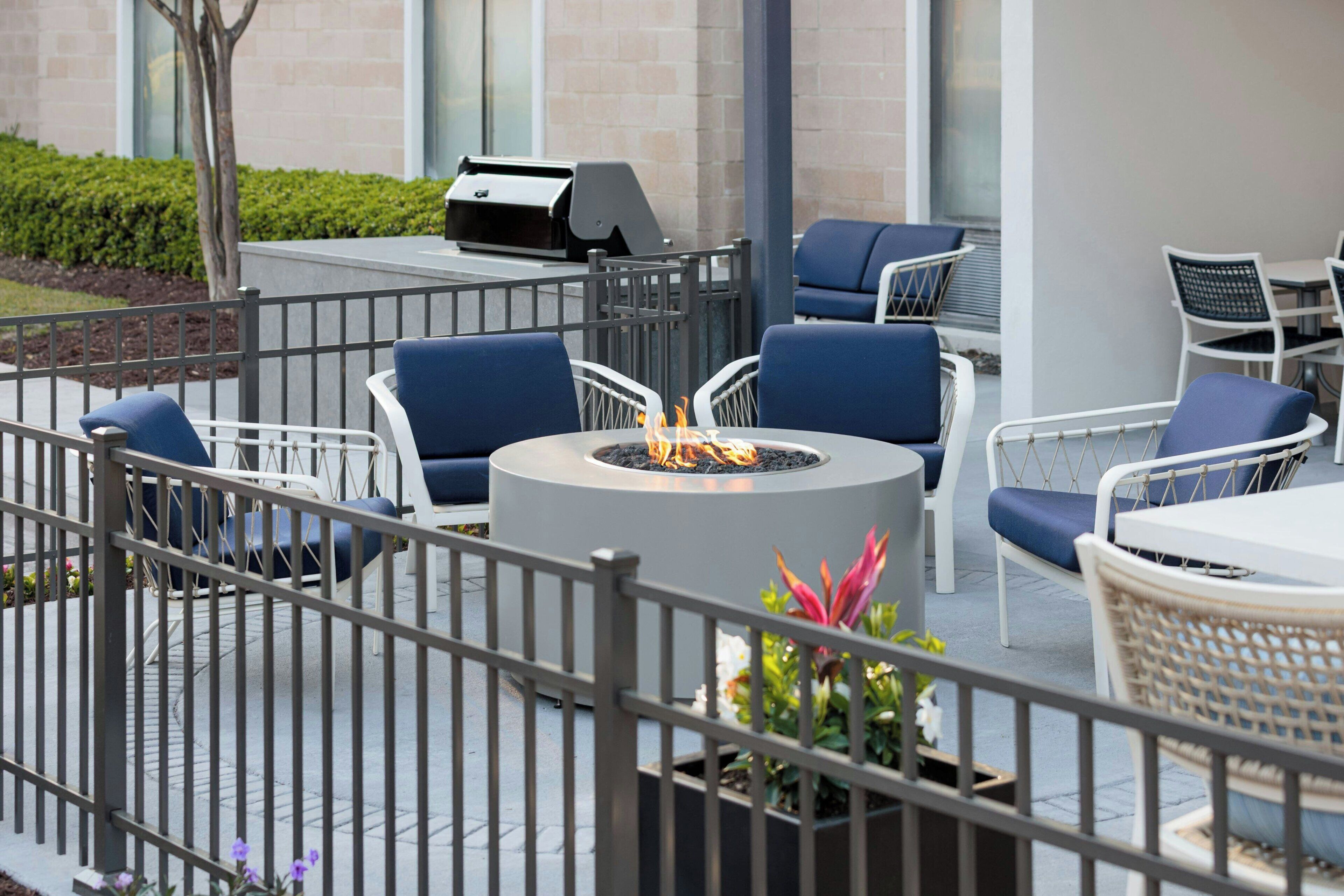 An outdoor patio with a fire pit, seating, and a grill.