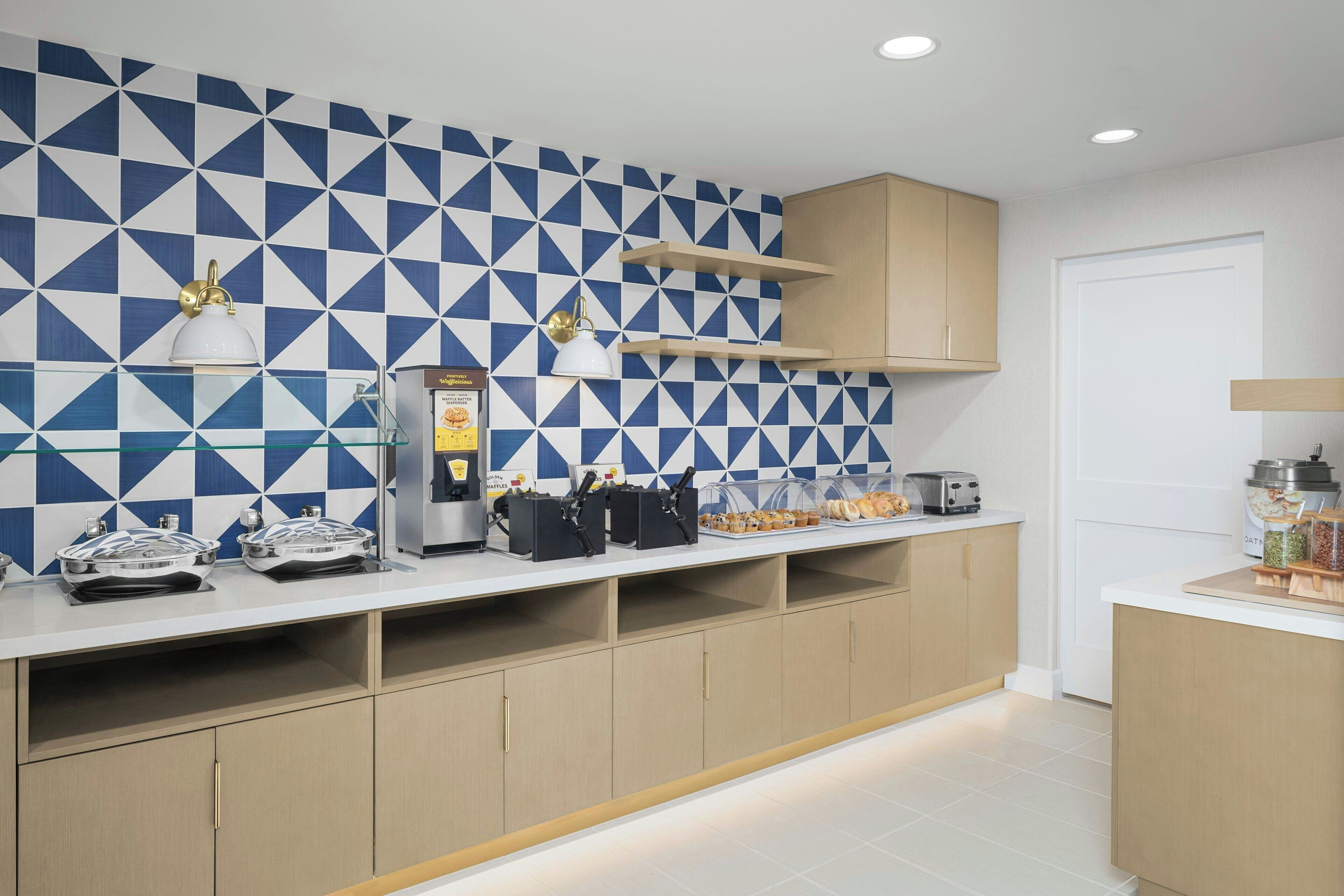 A modern kitchen with a geometric backsplash, built-in appliances, and a clean, organized layout.