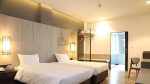 Een moderne hotelkamer met twee bedden, een bureau en een stoel.