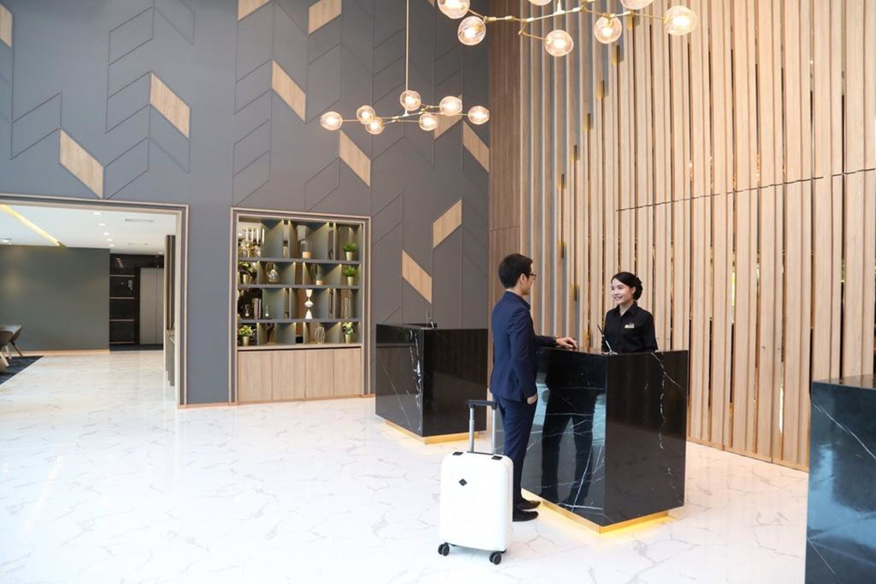 A reception area with a modern design, featuring a black reception desk, a wooden panel wall, and a geometric patterned wall.