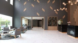 Een moderne lobby met een geometrisch patroon op de muur, een receptiebalie en een zithoek.