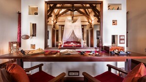 Una habitación con una mesa de madera, sillas, una cama con dosel y vistas por una ventana.