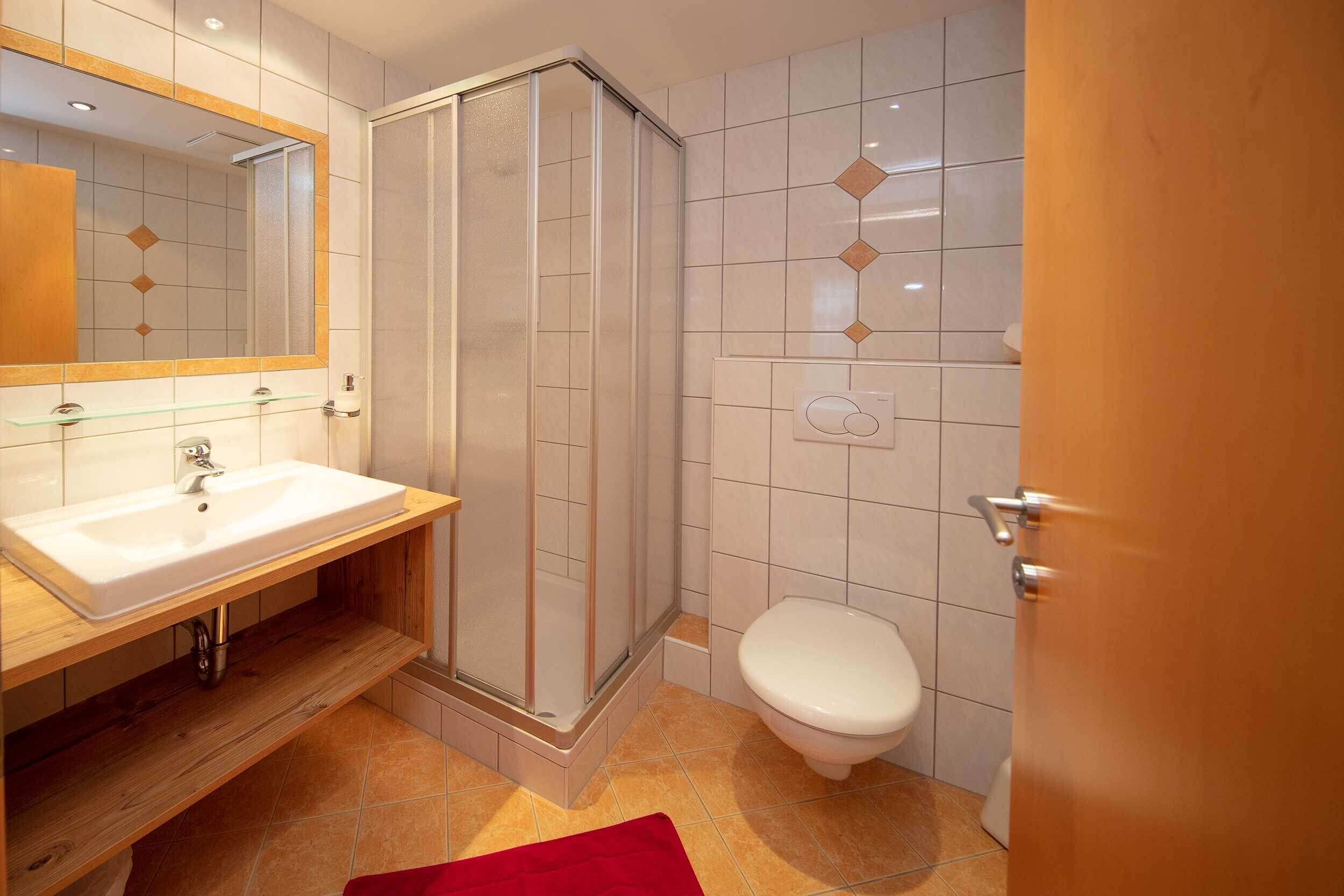 Een badkamer met een douchecabine van glas, een wit wastafel en een toilet.