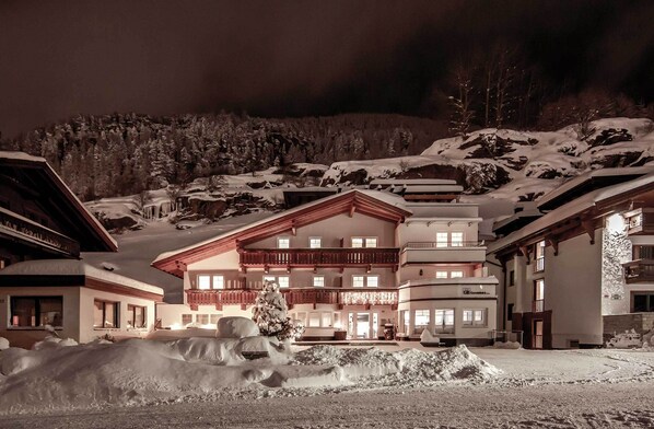 Un grand hôtel à plusieurs étages, dont la façade est recouverte de neige, et qui possède un balcon au deuxième étage.