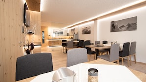 A modern dining area with wooden walls, a central table, and grey upholstered chairs. - GB Gondelblick (Soelden)