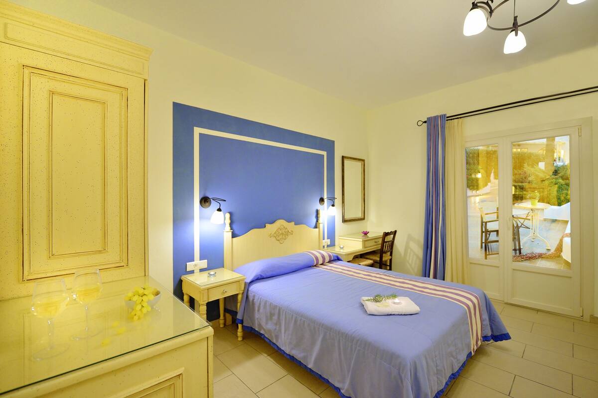 A bedroom with a bed, bedside tables, a desk, and a chair.