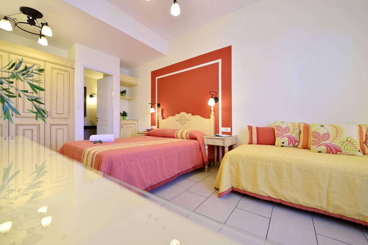 A hotel room with two beds, a large mirror, and a red accent wall.