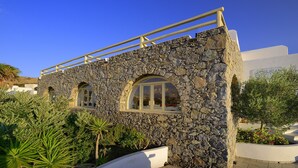 A stone building with arched windows and a white balcony railing. - Hotel Pelican (Mykonos)