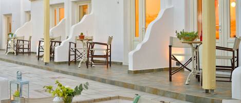 Un patio de hotel con mobiliario exterior, paredes blancas y suelo de baldosas.