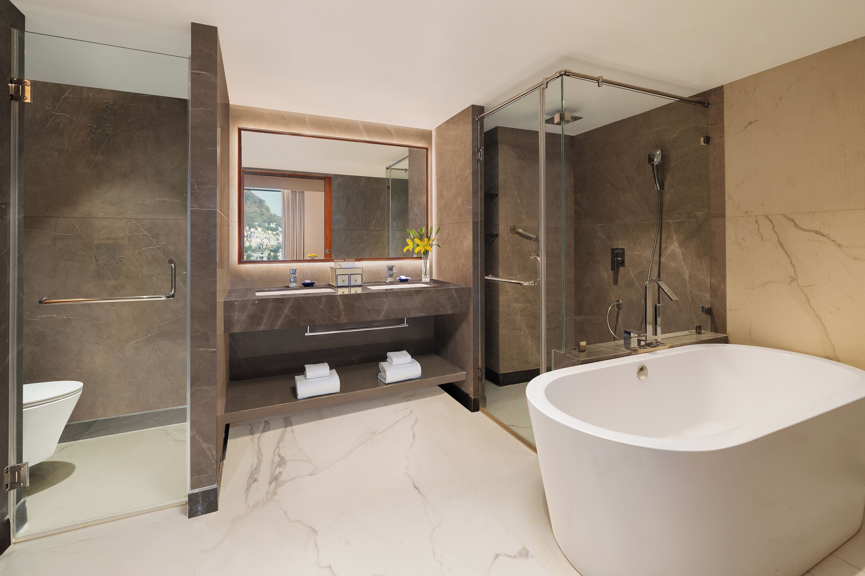 A modern bathroom with a large bathtub, a glass-enclosed shower, and a vanity with a mirror.