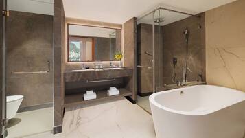 Un baño moderno con una bañera grande, una ducha con cerramiento de vidrio y un tocador con espejo.