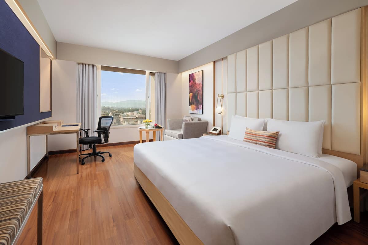 Hotelkamer met een groot bed, bureau, stoel, televisie en raam met uitzicht op de stad.