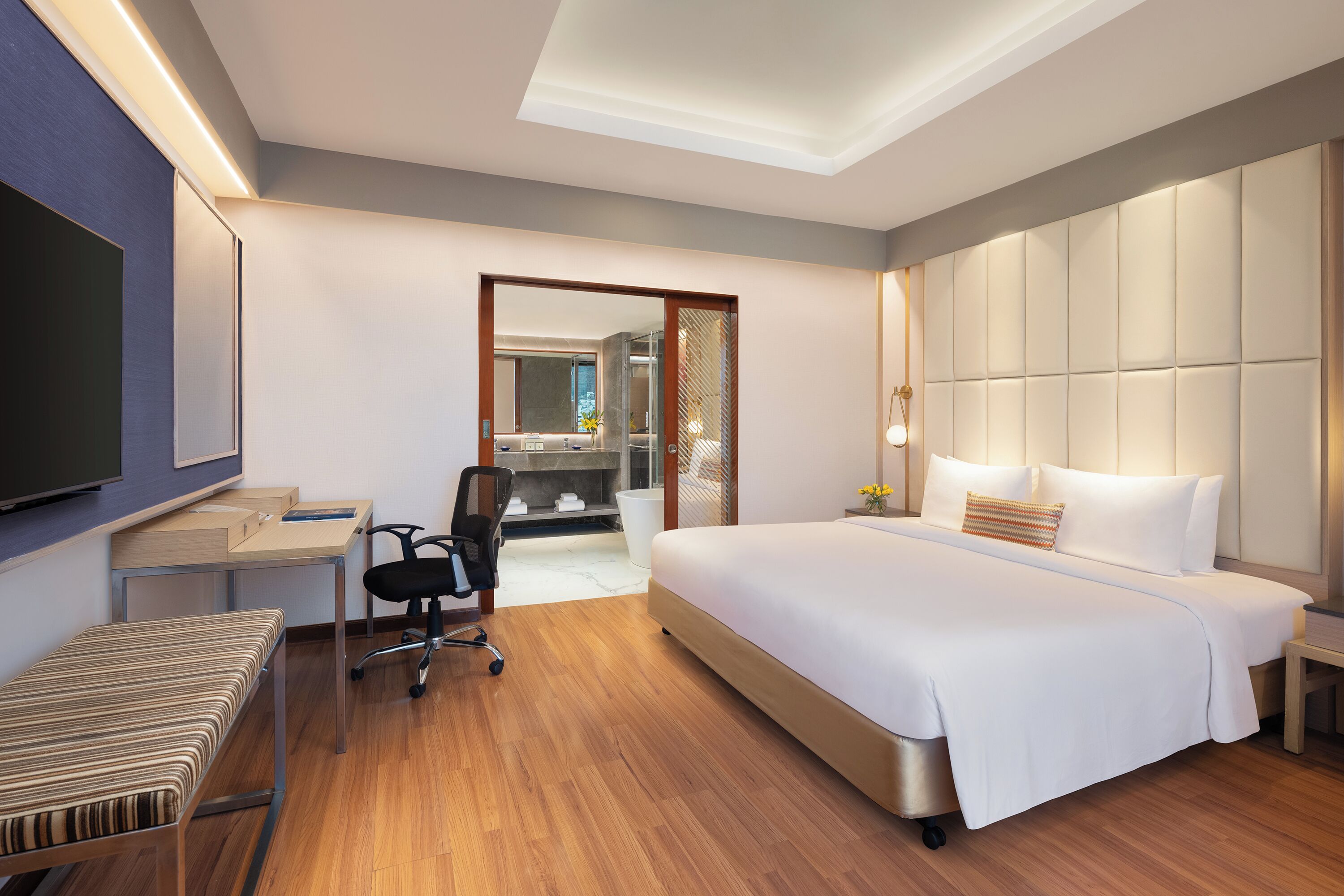 Une chambre d’hôtel moderne équipée d’un grand lit, d’un bureau, d’une chaise et d’un téléviseur.