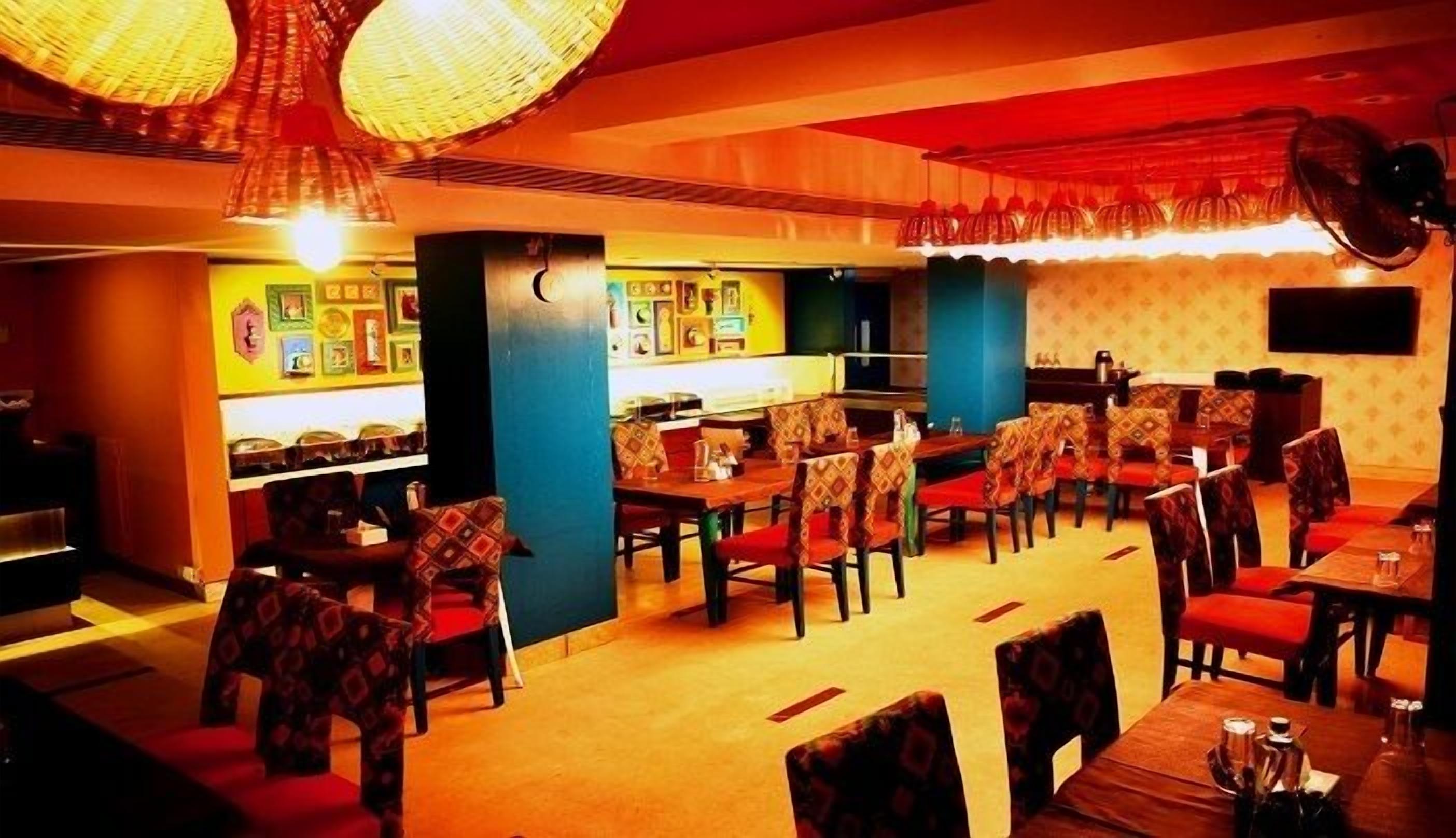 A restaurant with multiple tables and chairs, a bar area, and a wall decorated with pictures.
