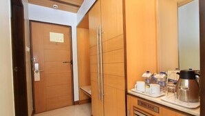 Ein Hotelzimmer mit einem Holzschrank, einer Minibar mit Kaffee und Tee sowie einem kleinen Tisch mit Spiegel.