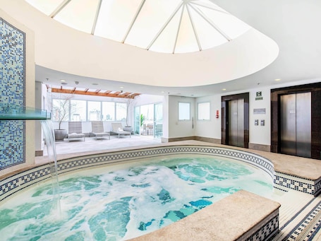 A modern indoor pool area with a clear view of the cityscape through large windows.