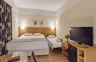Habitación de hotel con dos camas, un televisor, un escritorio y un armario.