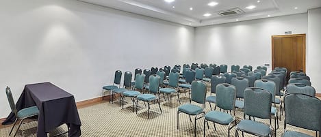 Ein Konferenzraum mit Stuhlreihen, einem Tisch und einer Tür mit der Aufschrift 'BAIDA'.