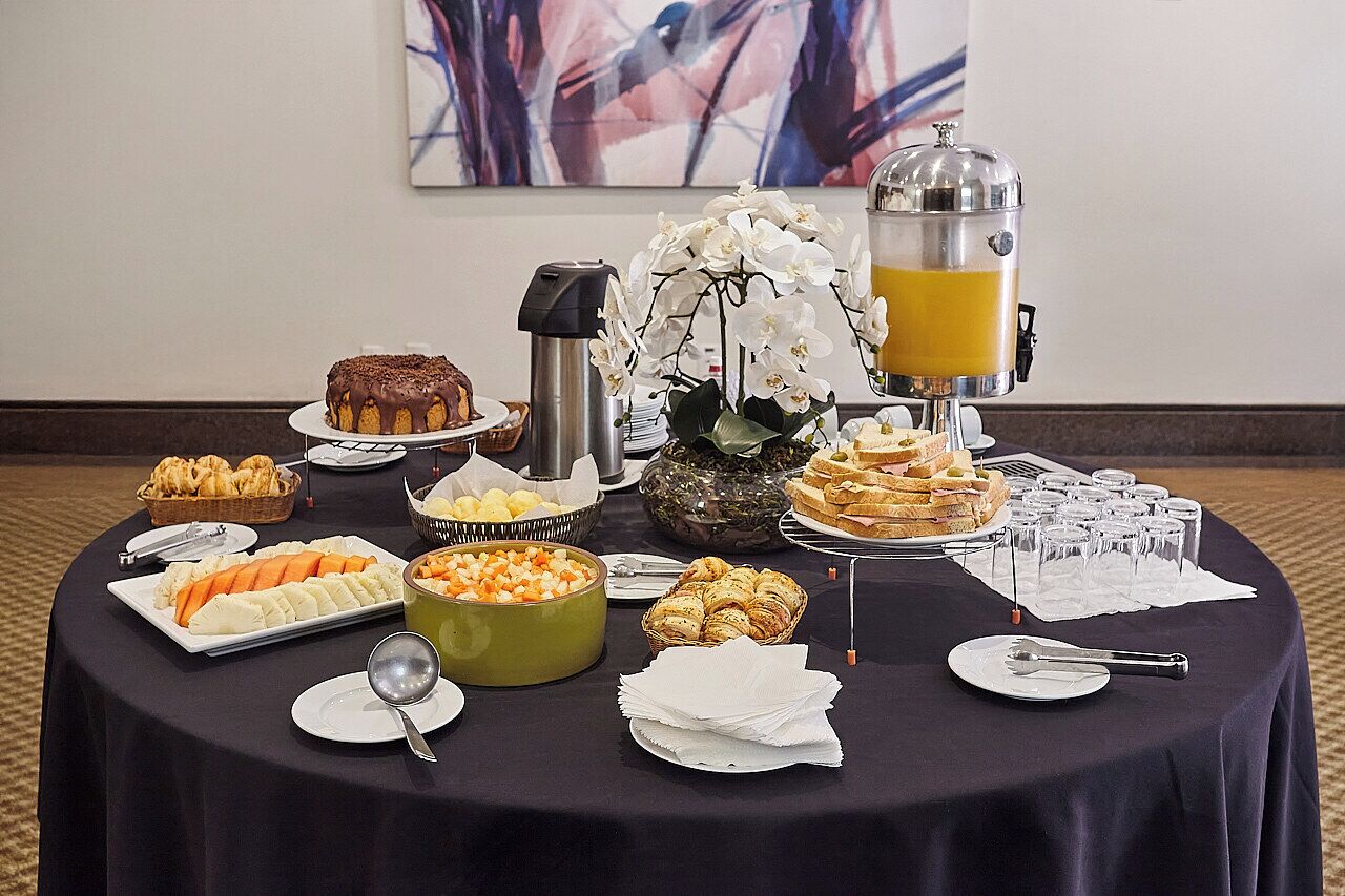 A buffet table with various food items, a juice dispenser, and a decorative orchid centerpiece.