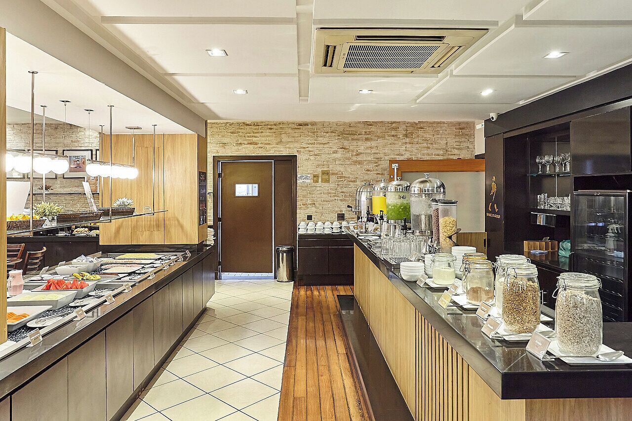 Una cocina de hotel moderna con un bufé, una pared de ladrillo y suelo de madera.