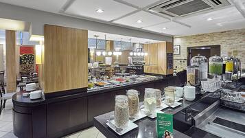 Un espace buffet proposant une variété de plats, un comptoir avec des assiettes et des couverts, et un panneau indiquant un avantage pour les clients.