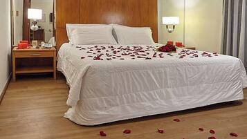 A hotel room with a large bed, wooden headboard, bedside tables, and a mirror.