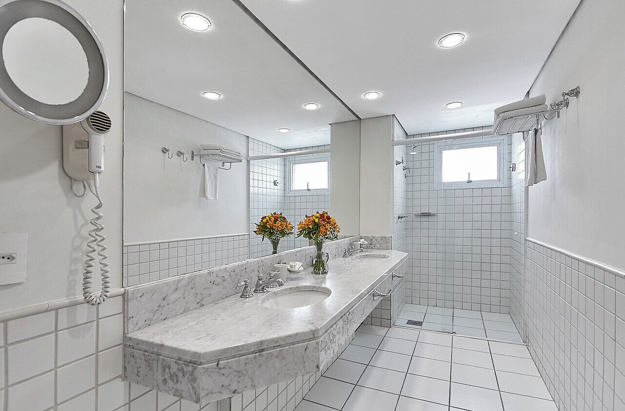 Een badkamer met een marmeren wastafelmeubel, twee wastafels, een spiegel en een douche.
