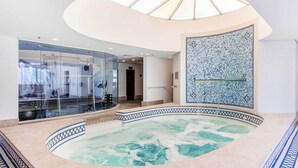 Una piscina con diseños de mosaicos, una cubierta de vidrio y un tragaluz.