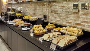 Un bufé con panes, pasteles y un fondo de pared de ladrillo.