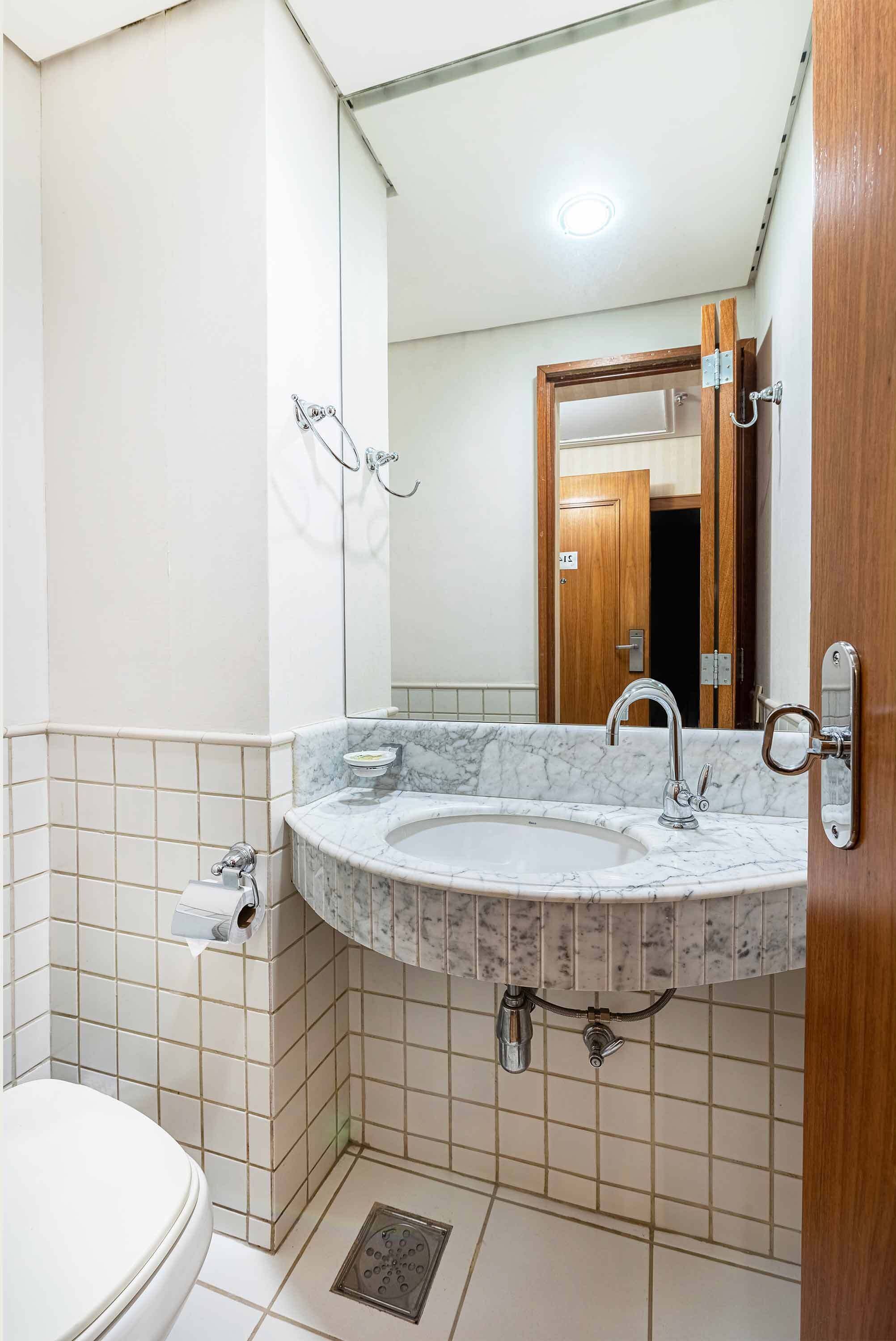 Un baño con lavamanos de mármol, inodoro y espejo.