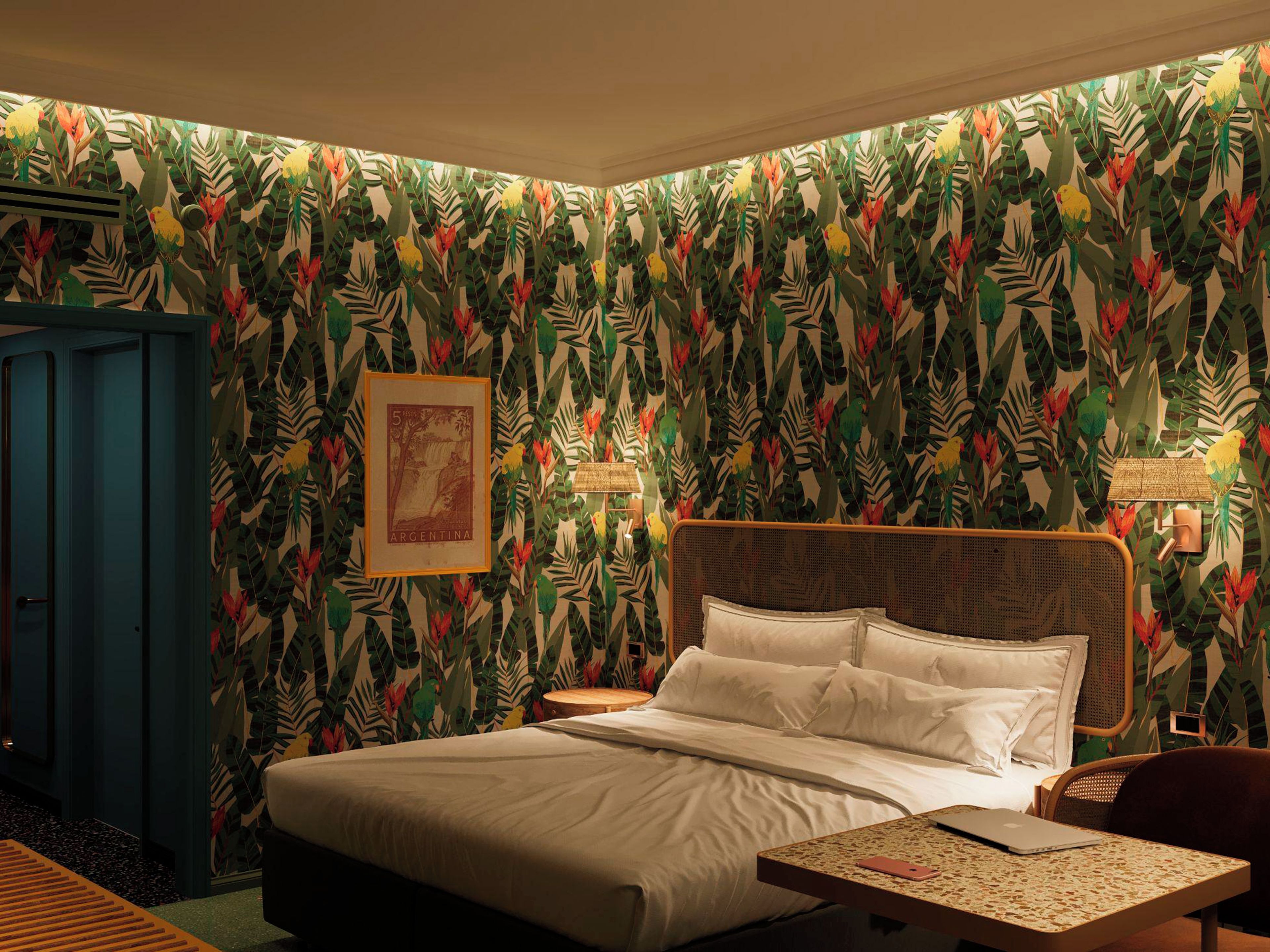 A room with a bed, a desk, and a wall with a tropical leaf pattern.