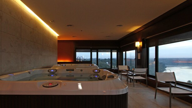 Un spa moderno con jacuzzi, ventanas amplias y vistas a la ciudad.