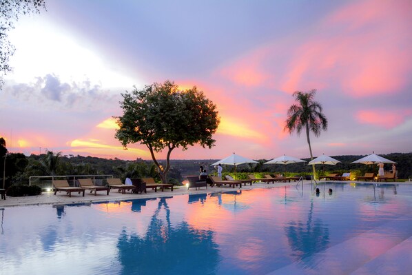 Relax by the serene pool surrounded by lounge chairs and umbrellas.