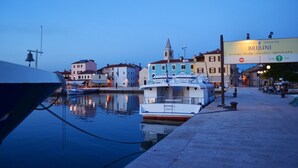 A waterfront scene with boats docked, a sign for Brijuni National Park, and buildings along the water's edge.