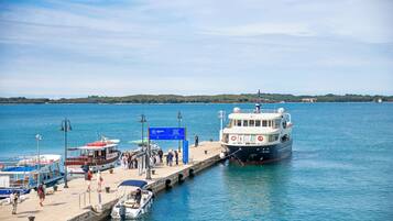 A pier with boats docked, a signboard, and a clear view of the water and distant land.
